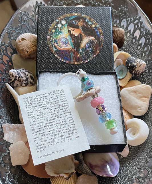 Decorative box with a colorful pendant and shell-themed card on a textured surface.